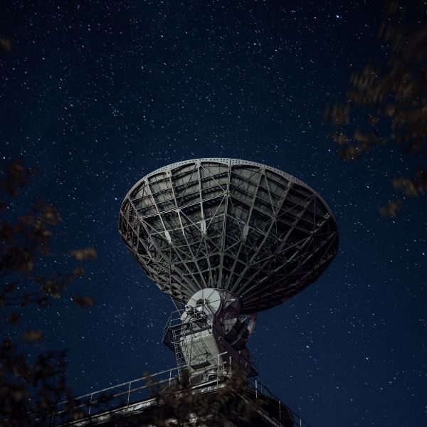 A large satellite dish is silhouetted against a starry night sky, conveying a sense of mystery and exploration_v2