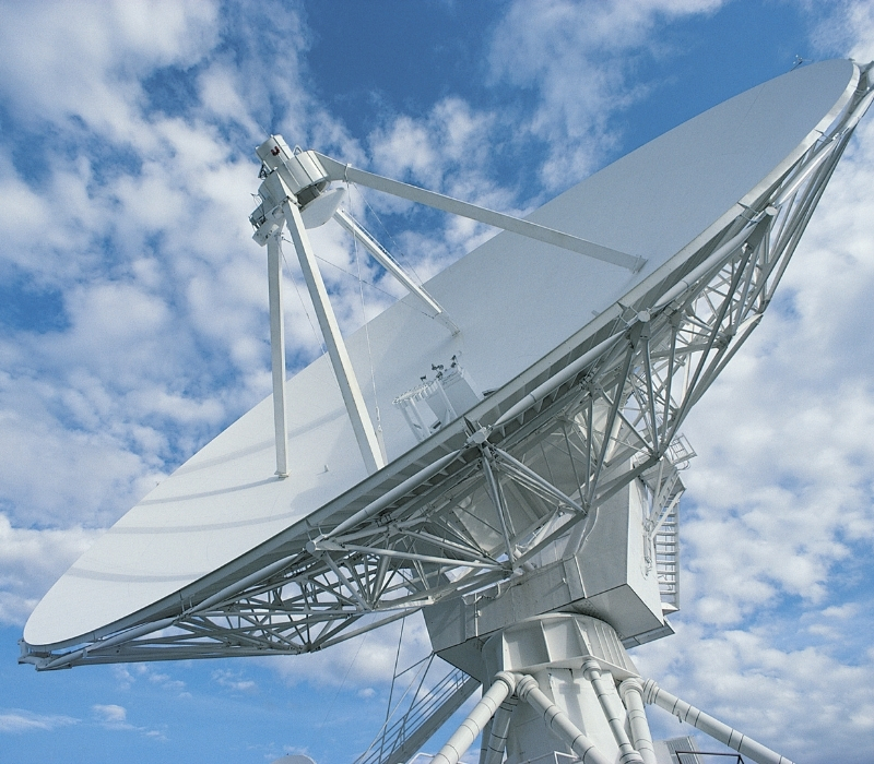 Large white satellite dish against a vibrant blue sky with scattered clouds